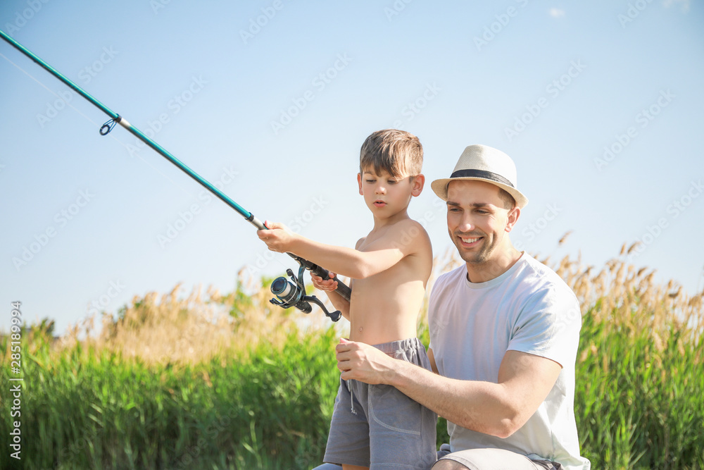 Father and son fishing together on river