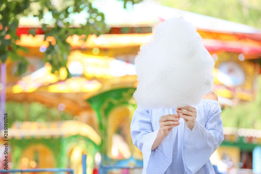 Woman with sweet cotton candy in amusement park