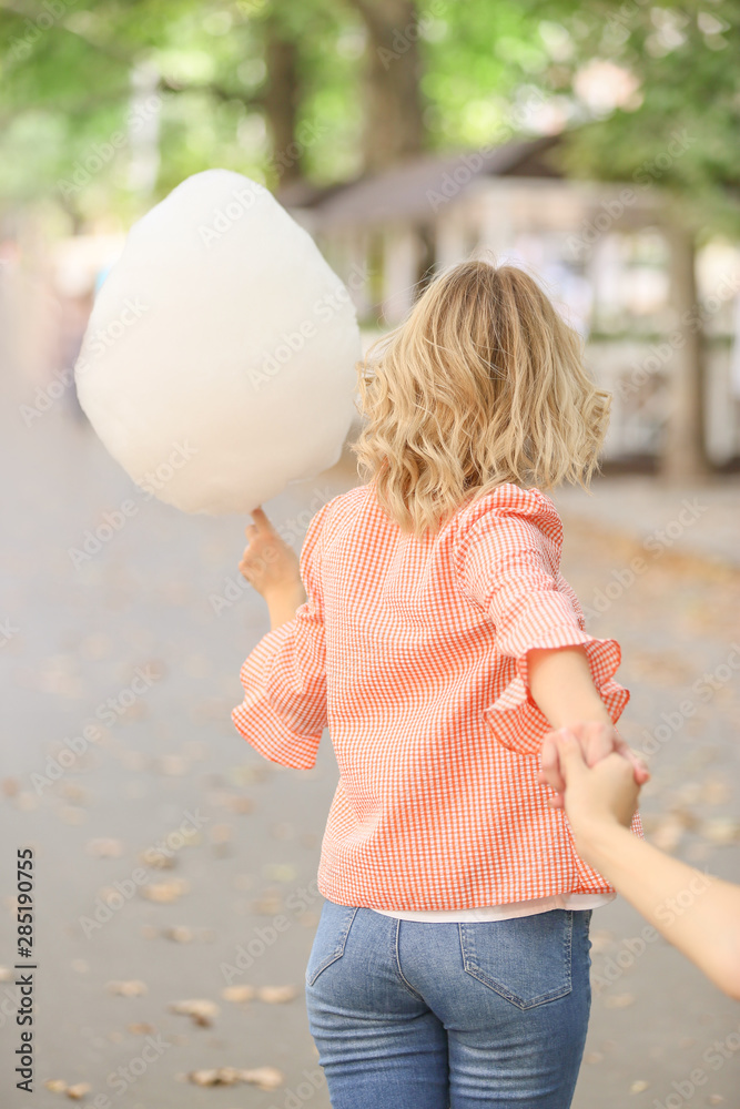 Woman with sweet cotton candy outdoors, back view