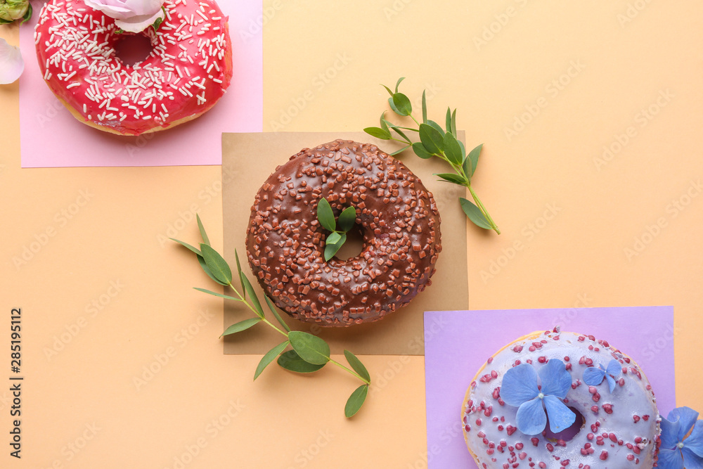 Sweet tasty donuts and flowers on color background