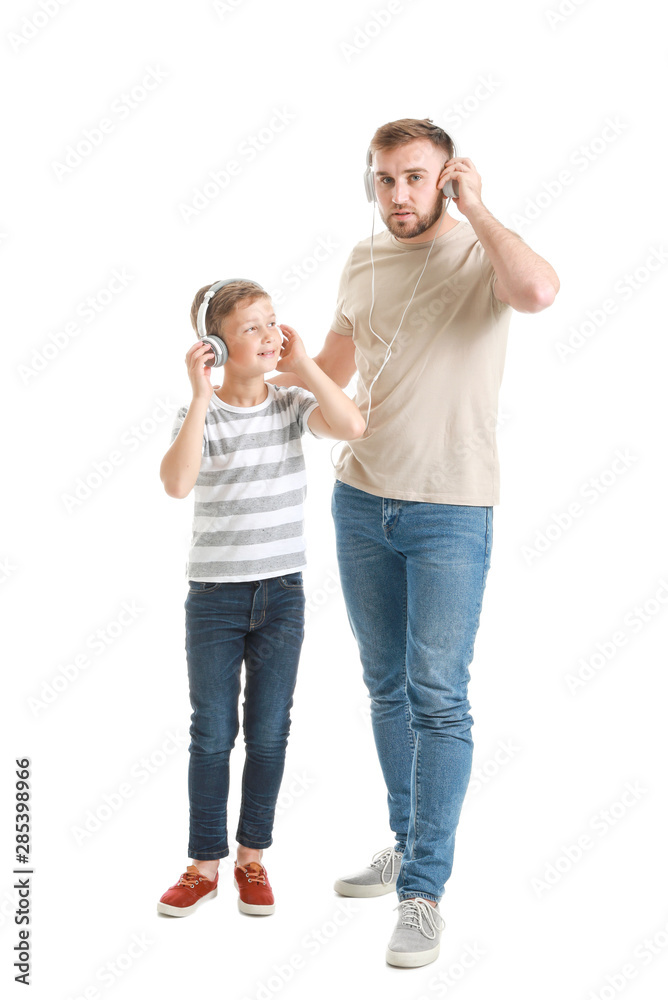 Portrait of happy father and son listening to music on white background