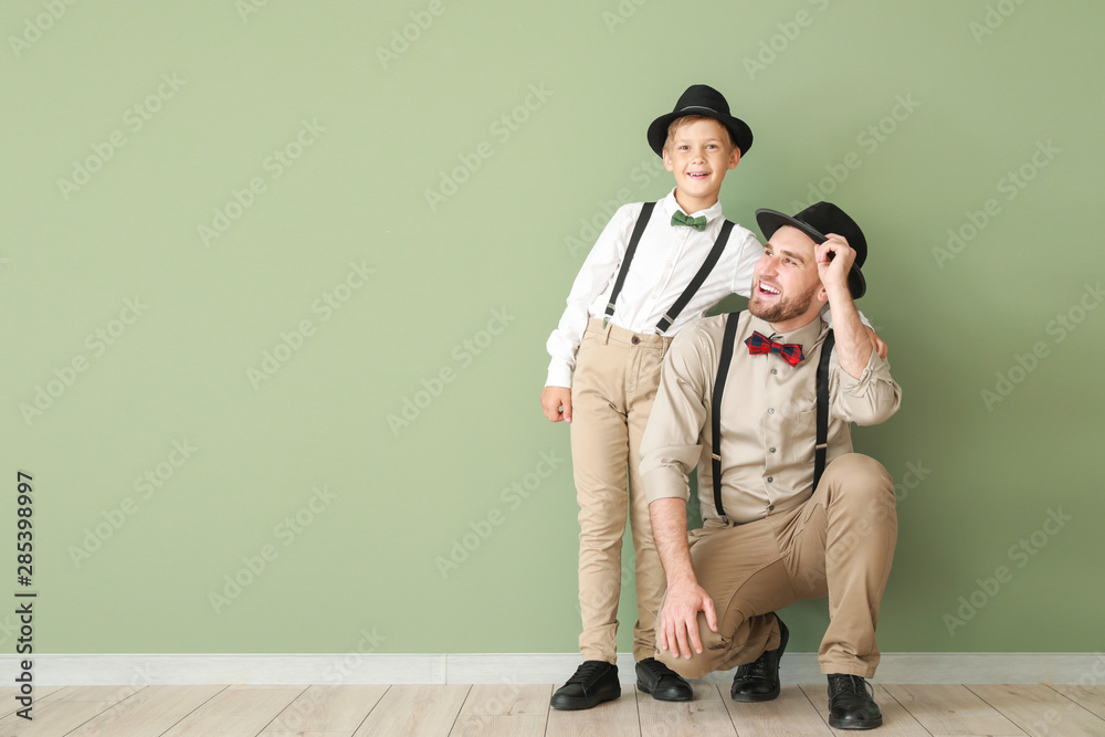 Portrait of fashionable father and son near color wall