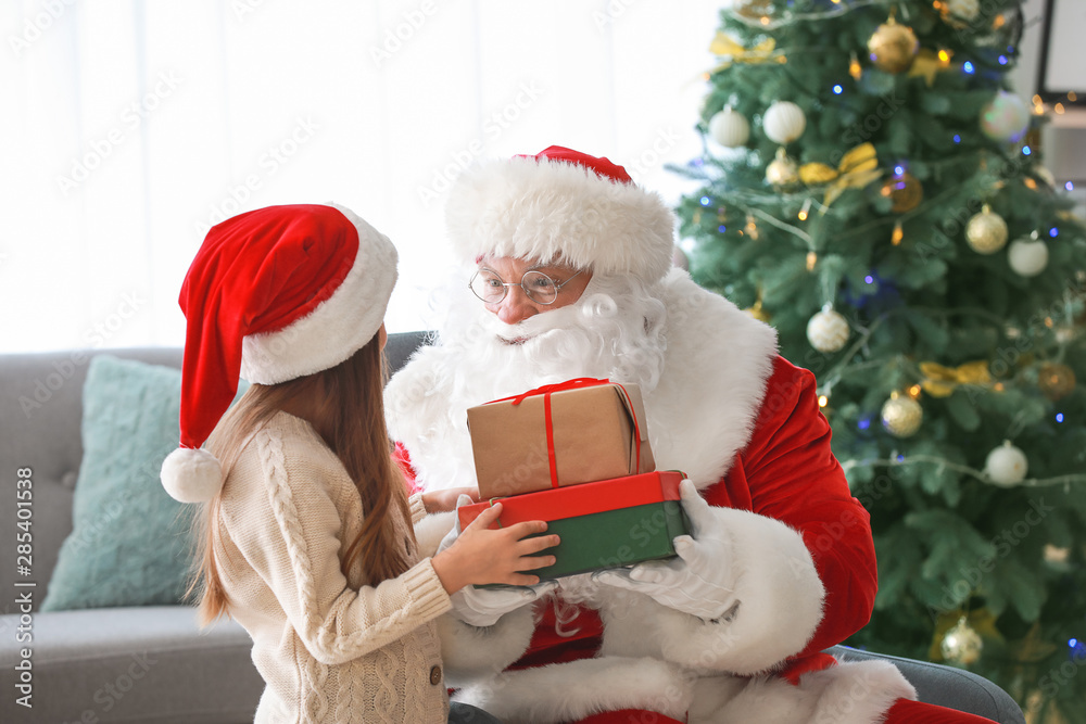 Santa Claus with gifts and little girl in room decorated for Christmas