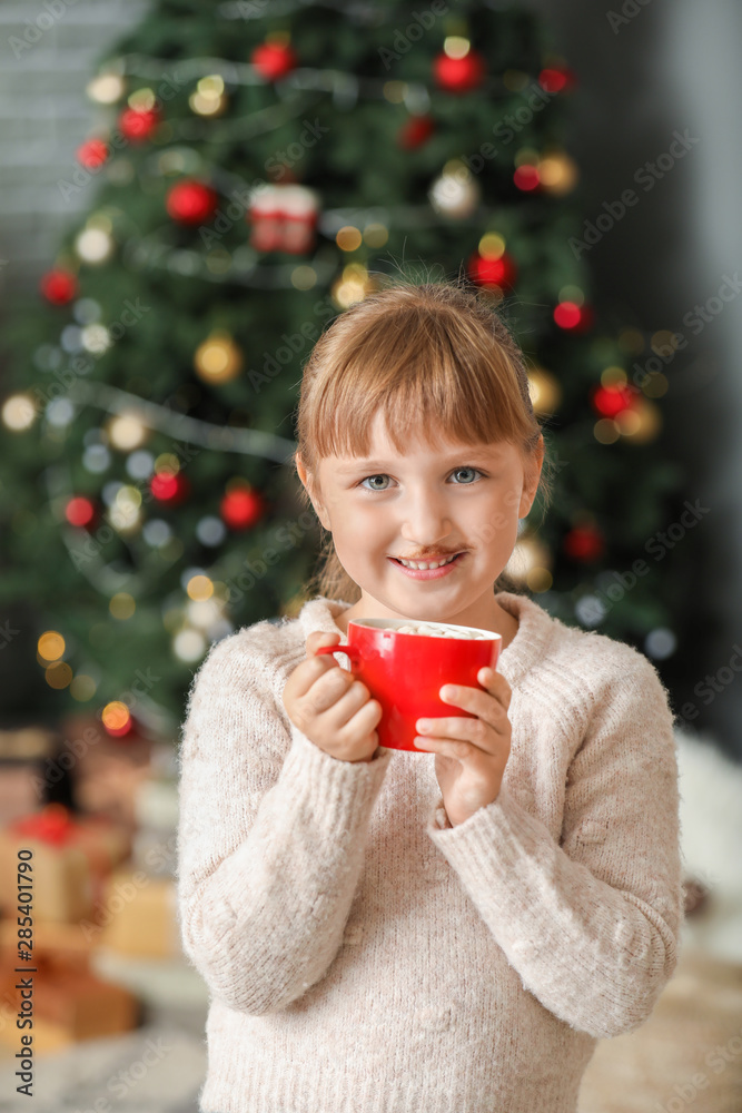 Cute little girl drinking hot chocolate at home on Christmas eve