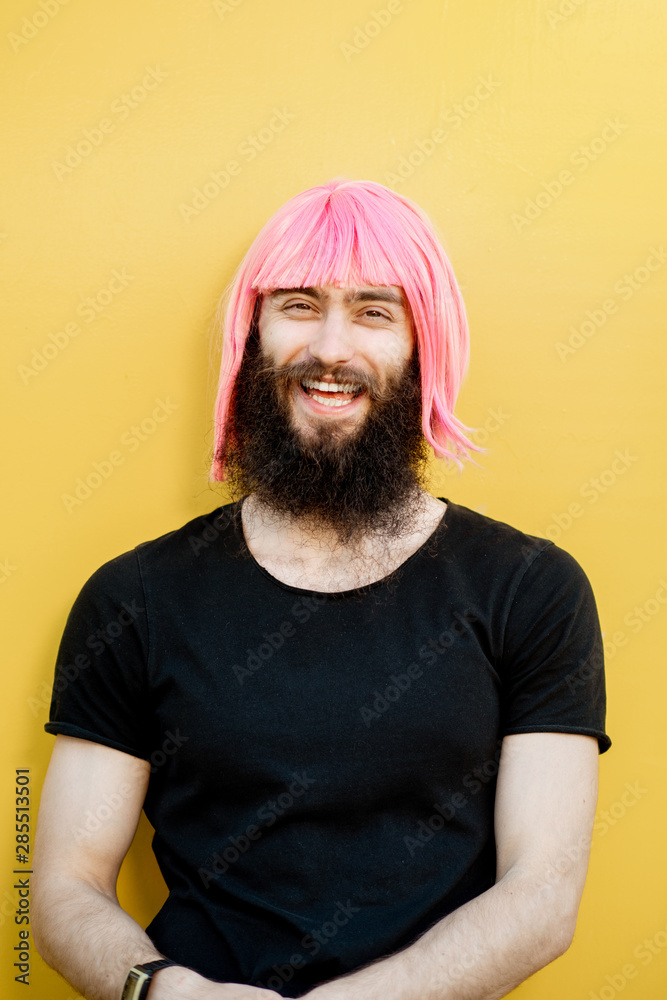 Funny portrait of a stylish playful man with beard and long color hair with expressive emotions on t