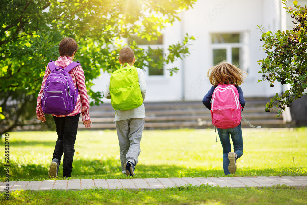 Children with rucksacks standing in the park near school