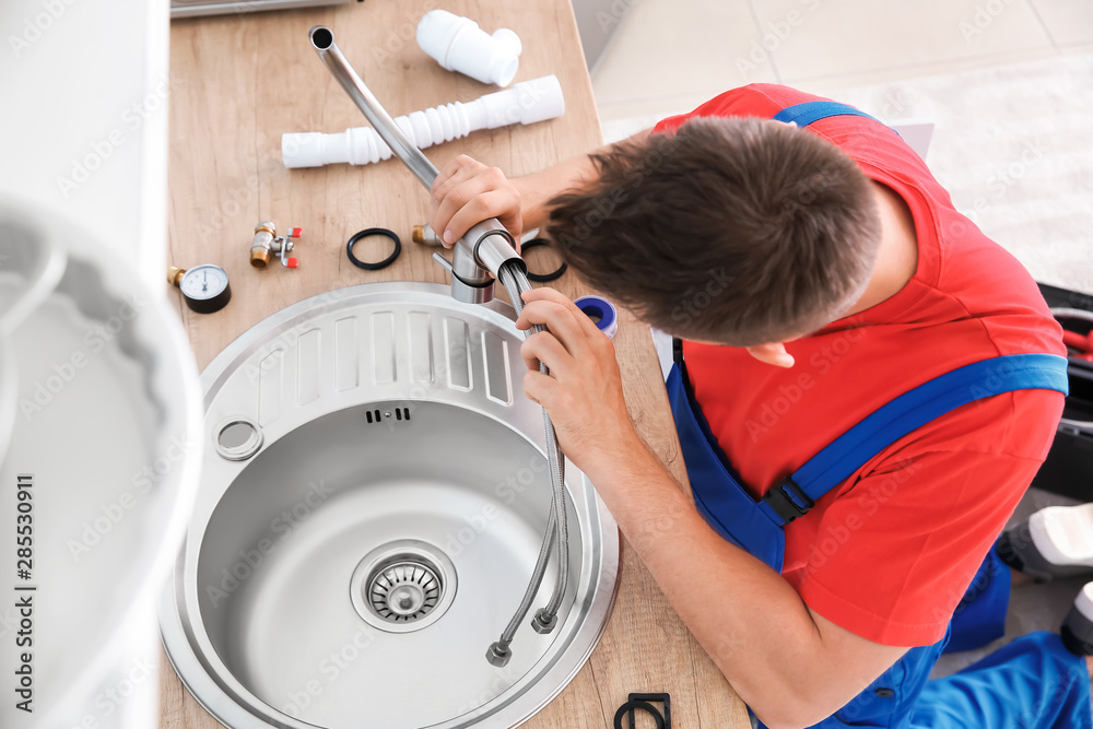 Plumber installing sink in kitchen