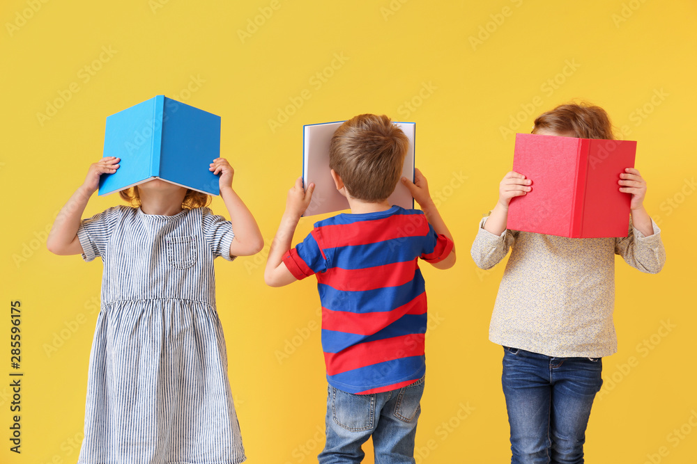 Cute little children reading books on color background