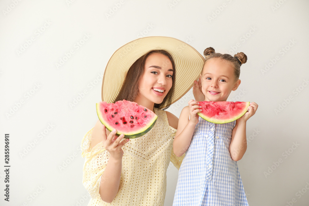 美丽的年轻女子和可爱的小女孩，浅色背景下有新鲜的西瓜