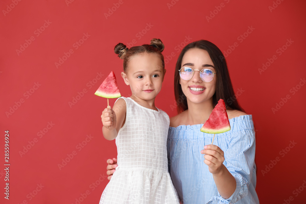 美丽的年轻女人和可爱的小女孩，背景是新鲜的西瓜