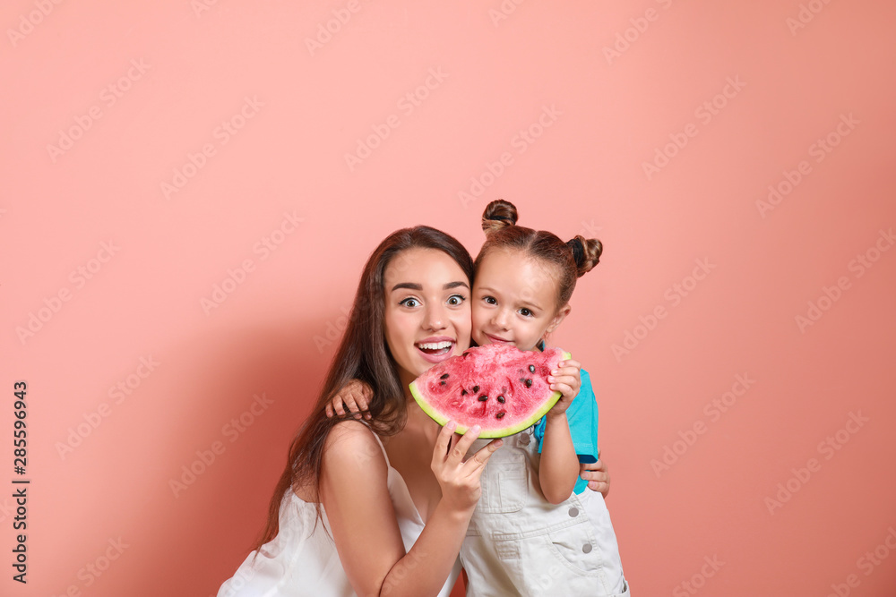 美丽的年轻女人和可爱的小女孩，背景是新鲜的西瓜