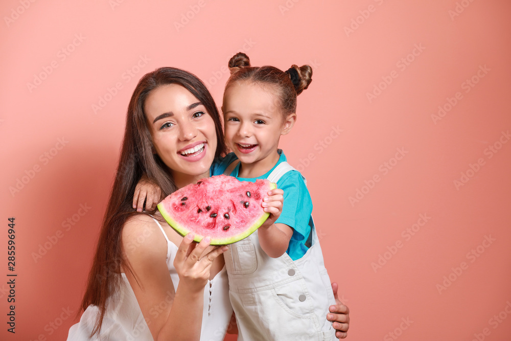 美丽的年轻女人和可爱的小女孩，背景是新鲜的西瓜