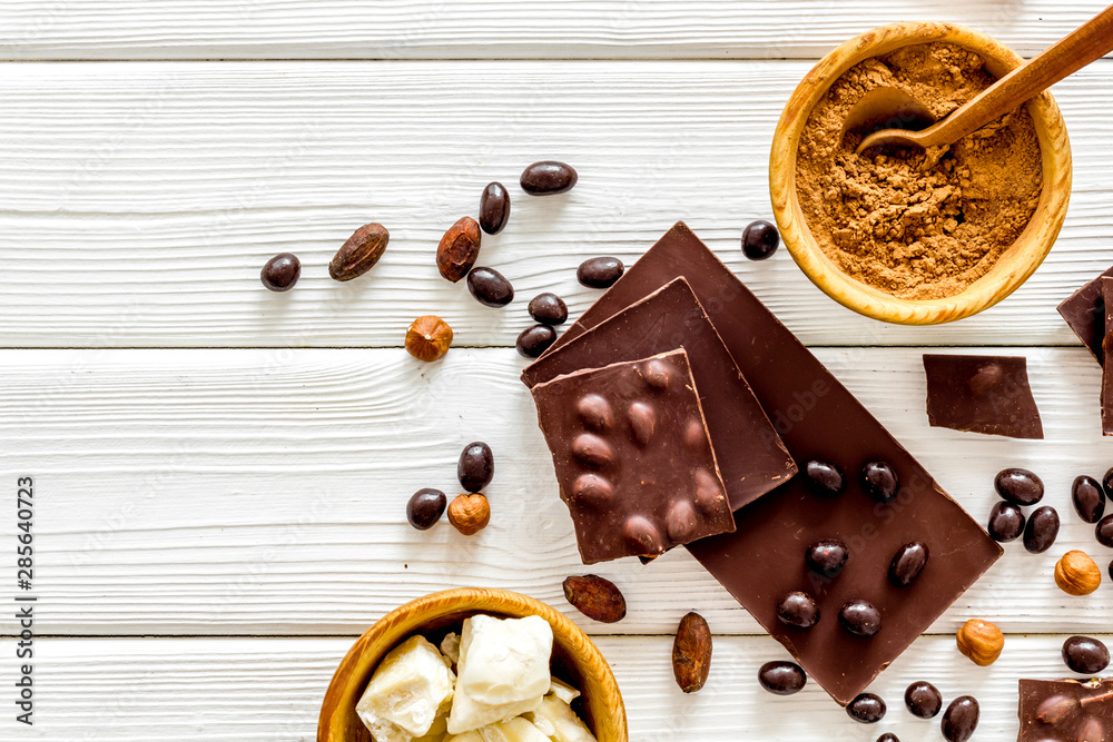 Chocolate with nuts and its ingredients on white wooden background top view copyspace