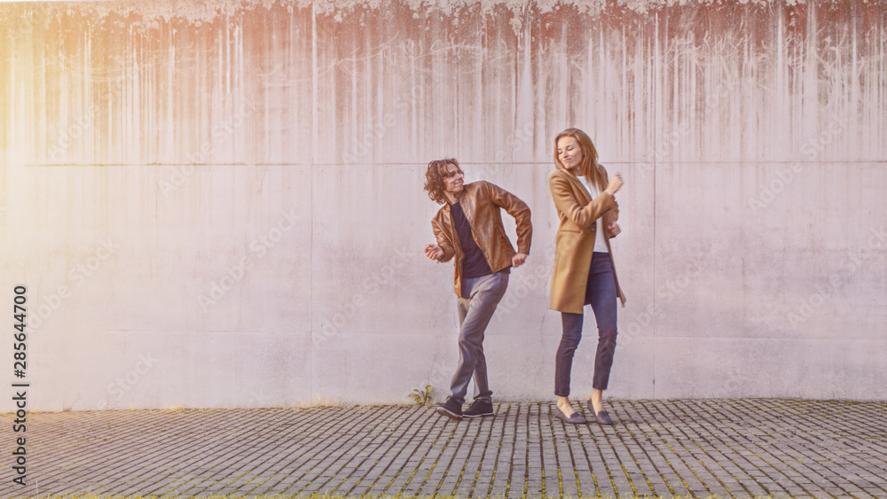 Cheerful Girl and Happy Young Man with Long Hair are Actively Dancing on a Street While a Businessma