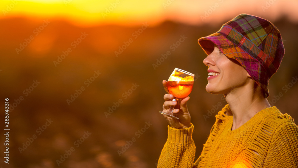 美丽的秋天女人喝着橙色的aperol（红酒）杯看日落-奢华的生活方式b