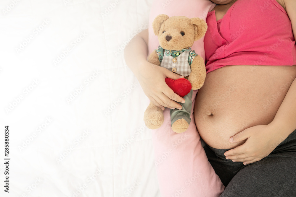 Happy pregnant woman sleeping on bed in bedroom at home for resting and stress relief. The young exp