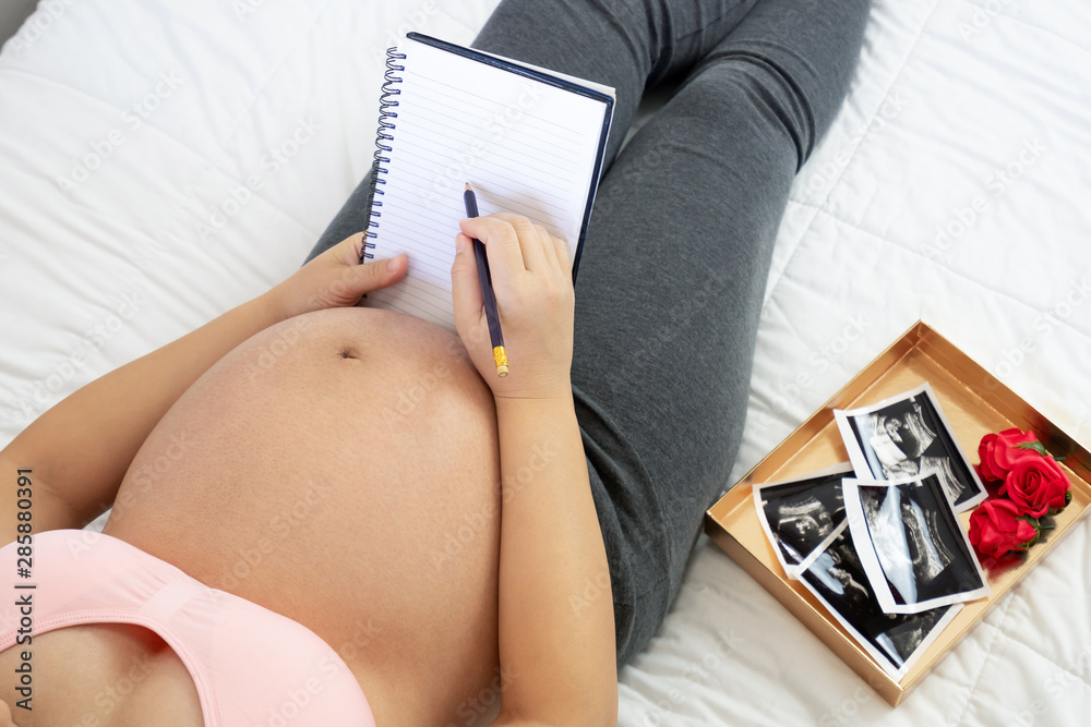 Pregnant woman feeling happy at home while taking care of her child. The young expecting mother hold