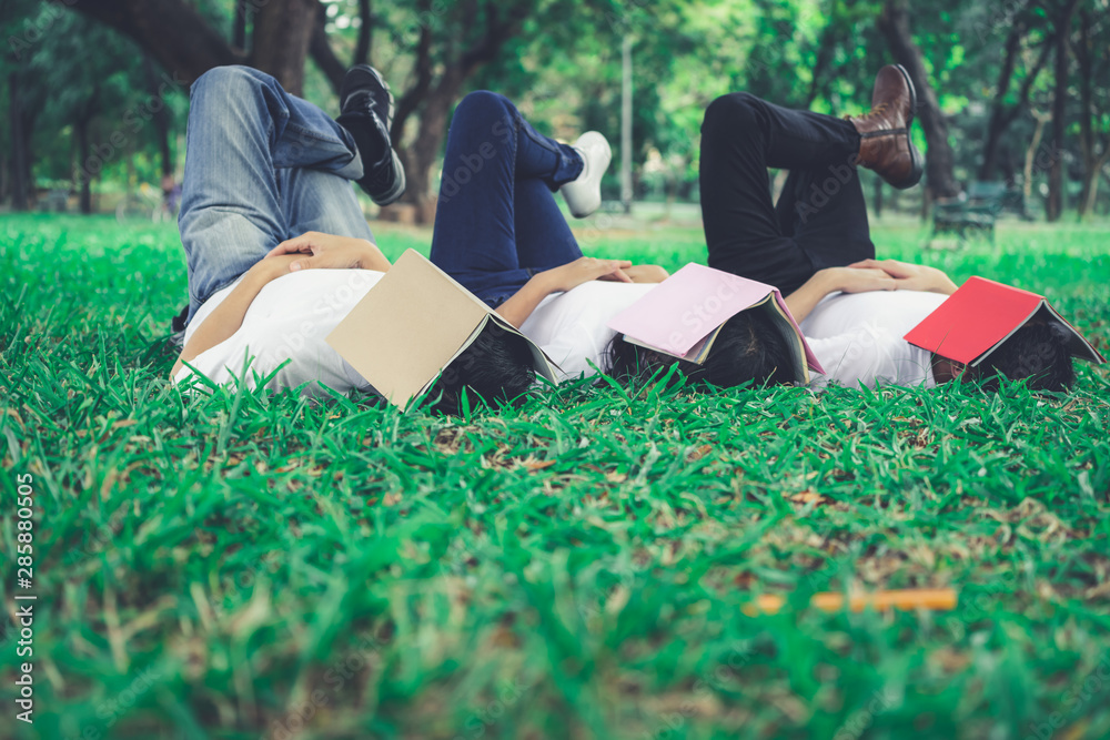 Funny students sleeping with books covering their face. Lazy and relaxation concept.