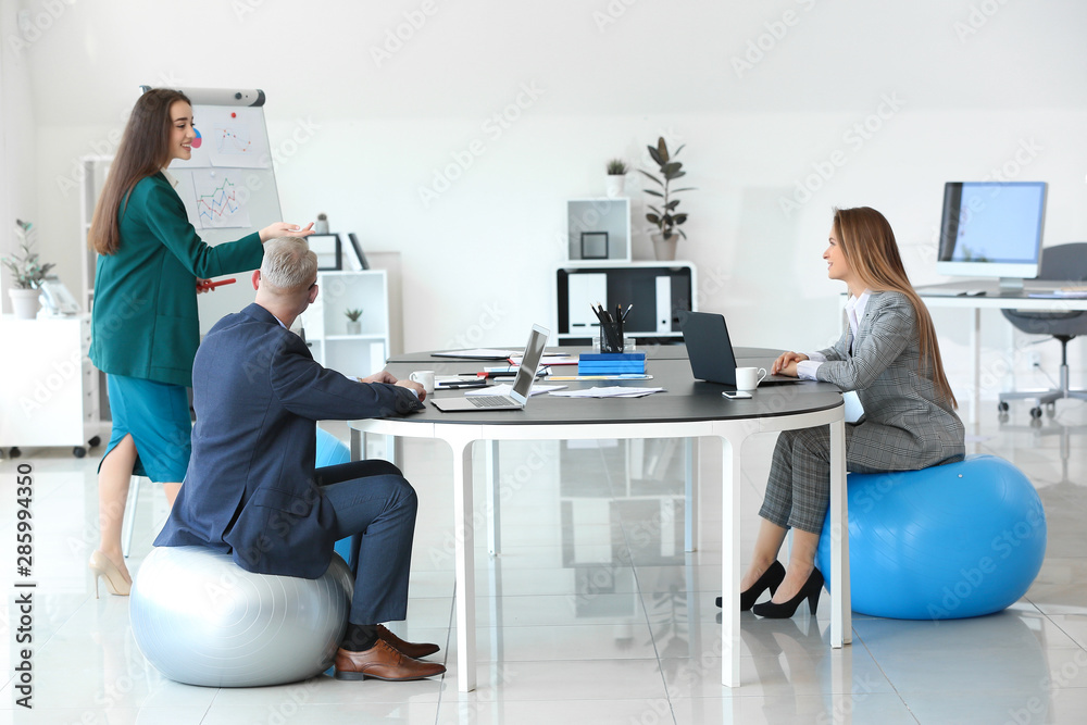 Young business people sitting on fitballs while working in office