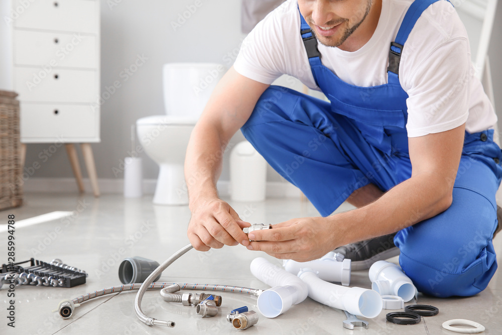 Plumber with tools working in restroom