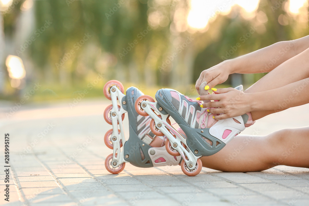 Teenage girl putting on roller skates outdoors