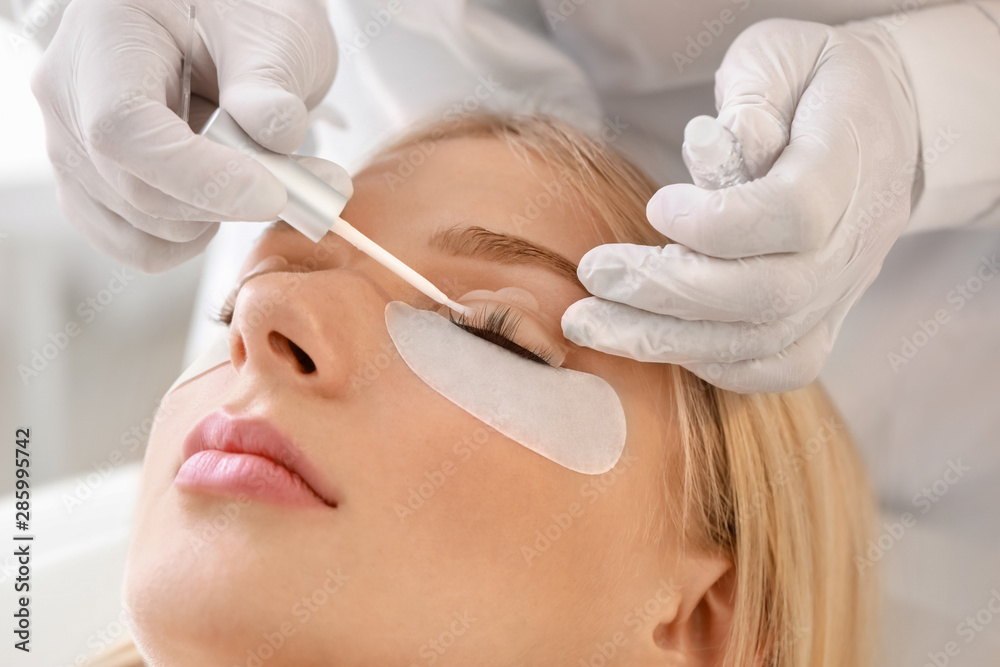 Young woman undergoing procedure of eyelashes lamination in beauty salon, closeup