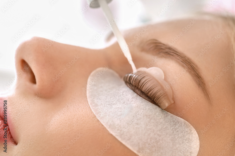 Young woman undergoing procedure of eyelashes lamination in beauty salon, closeup