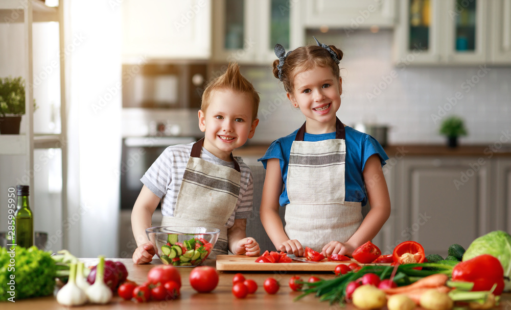 Healthy eating. Happy children prepares  vegetable salad in kitchen