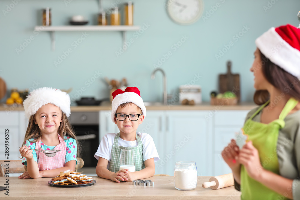 Woman and her little children preparing Christmas cookies at home