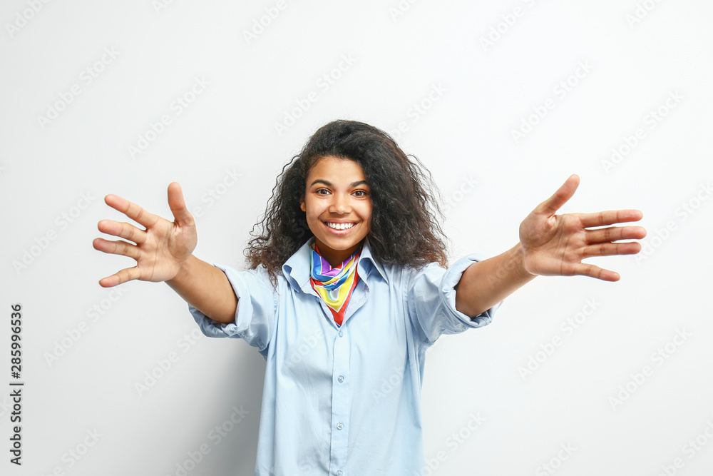 Happy young African-American woman on light background