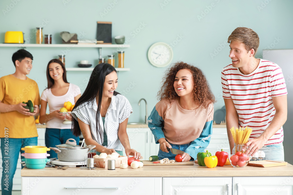 Happy friends cooking together in kitchen