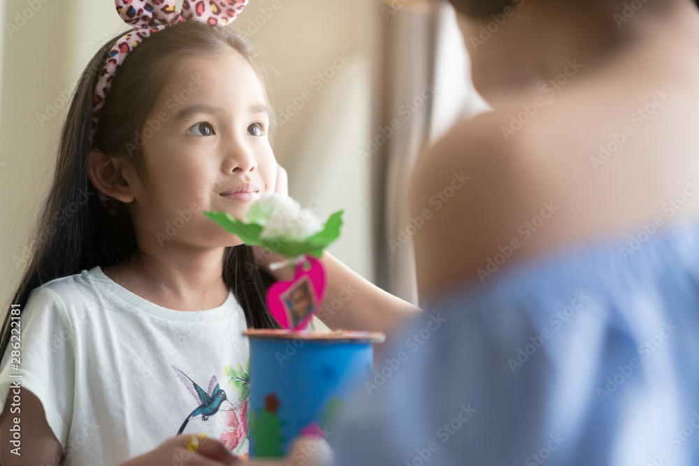 Asian cute daughter giving handmade present to her mother  with smile on mother’s day. The mother re