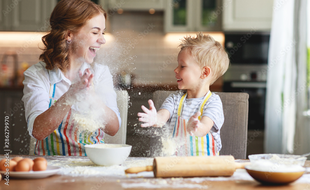 happy family in kitchen. mother and child preparing dough, bake cookies