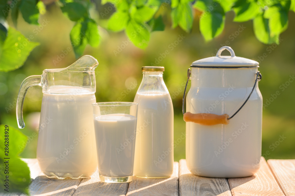 Glass and jug of fresh milk on wooden table