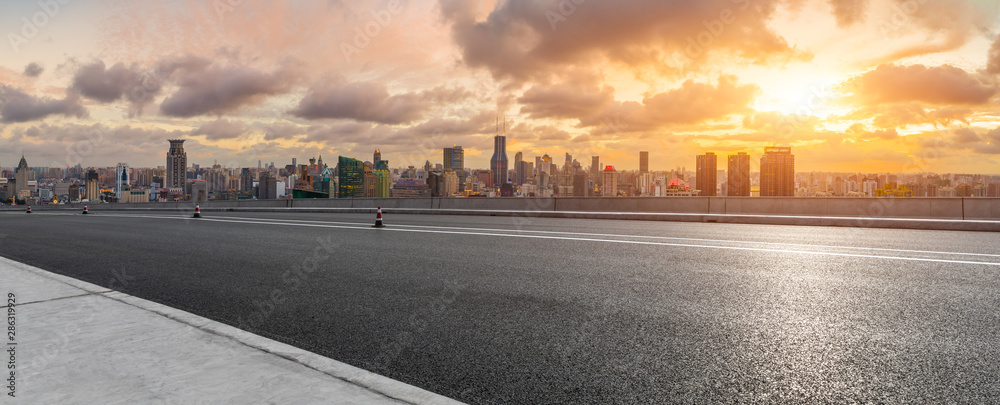 中国上海，落日余晖下，空旷的高速公路和城市天际线。