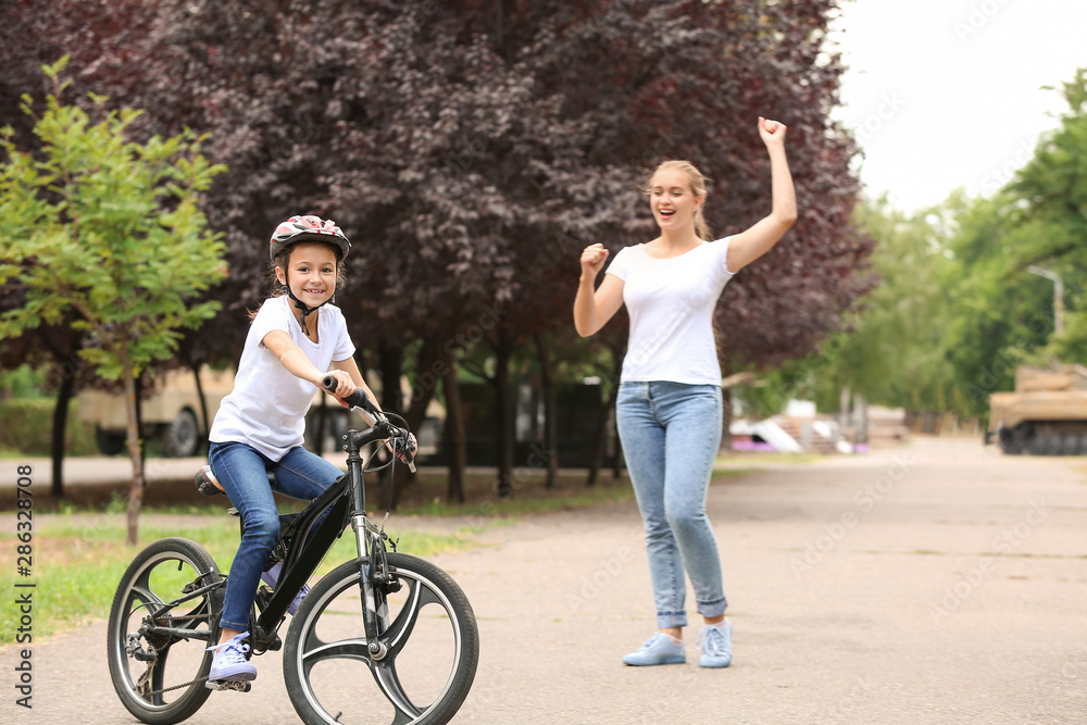 Mother proud of her daughter who learned to ride bicycle outdoors