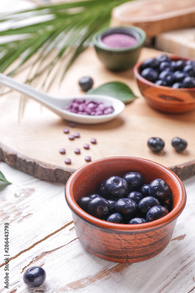 Bowl with fresh acai berries on wooden table