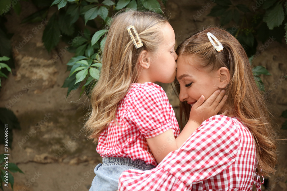 Portrait of beautiful woman and her little daughter outdoors