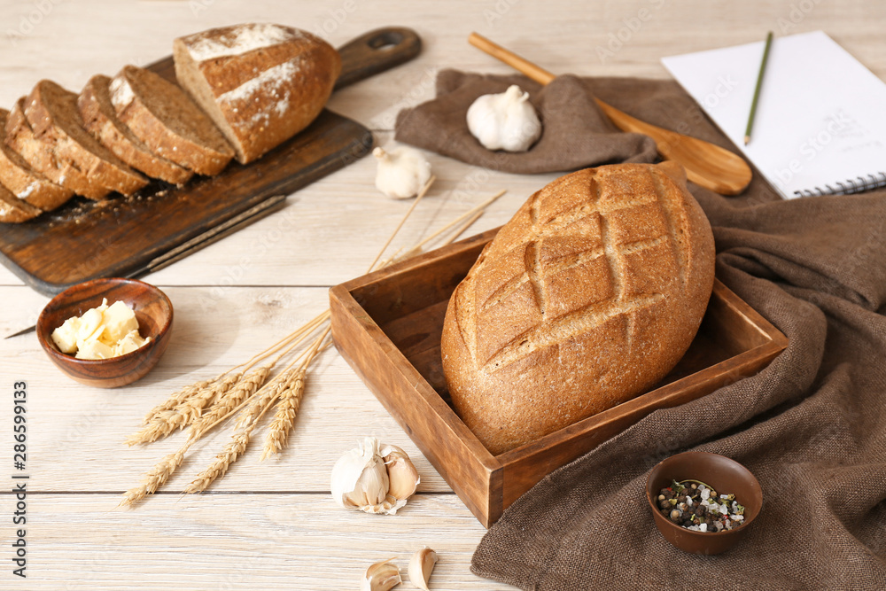 Tasty fresh bread with butter and spices on white wooden table