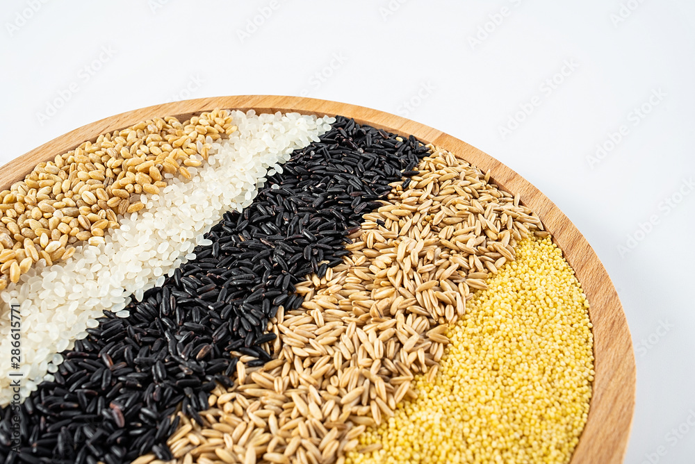 a wooden dish filled with whole grains cereal grain on a white background