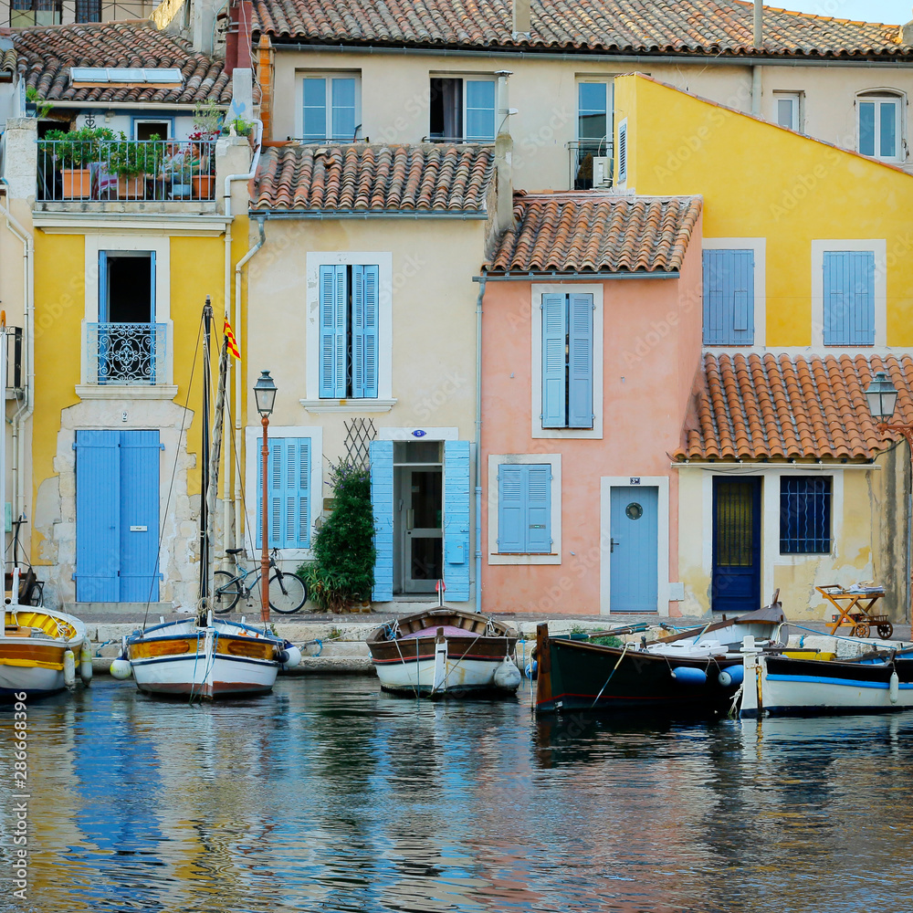  facade of mediterranean building with colorful shutter with river and boat