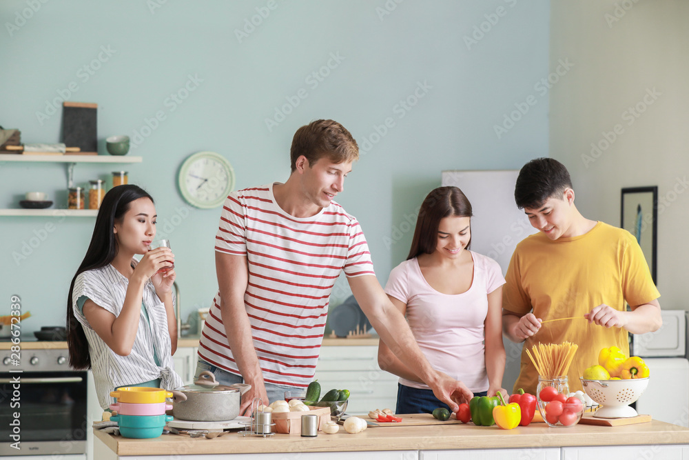 Happy friends cooking together in kitchen