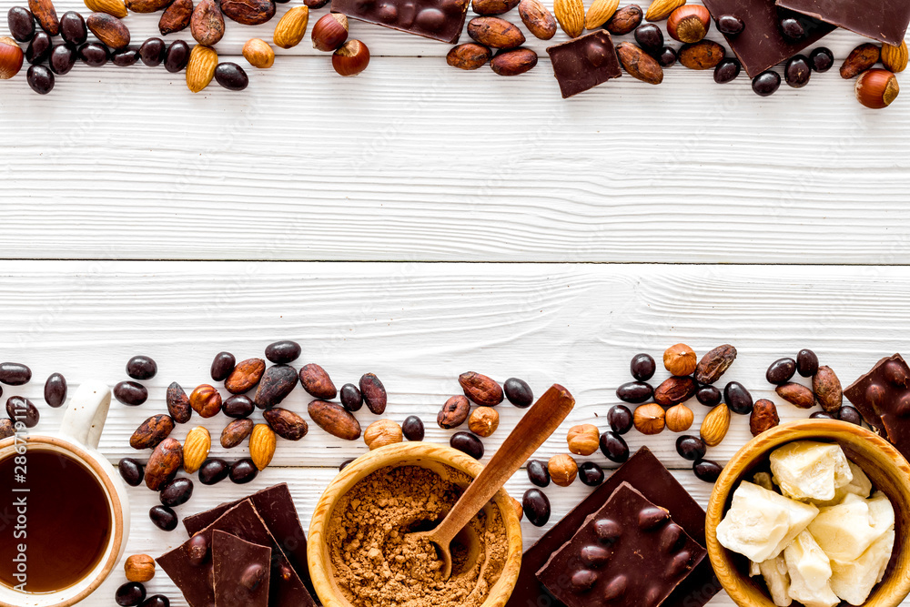 Chocolate with nuts and its ingredients on white wooden background top view copyspace