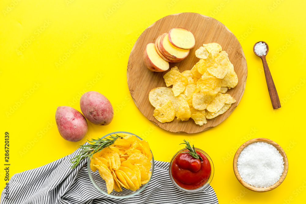 Cooking homemade potato chips with ketchup on yellow background top view