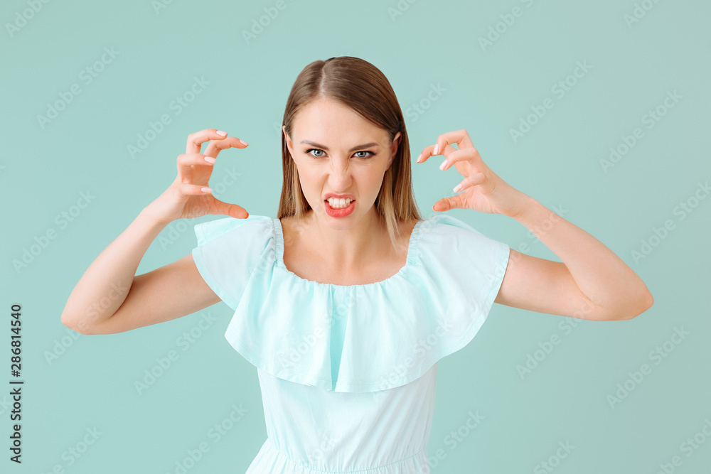 Aggressive young woman on color background