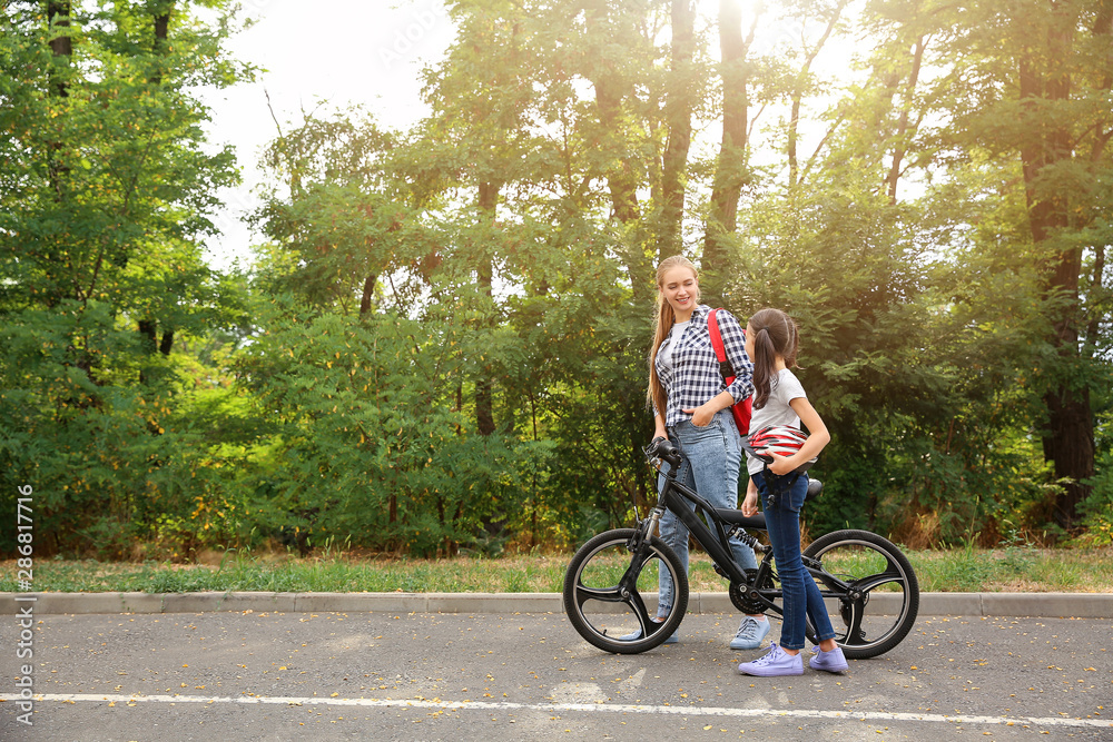 Woman and her little daughter with bicycle outdoors