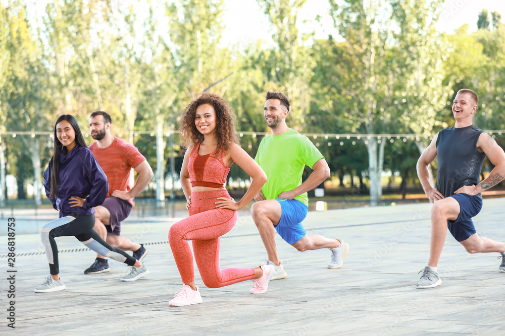 Group of young sporty people training together outdoors