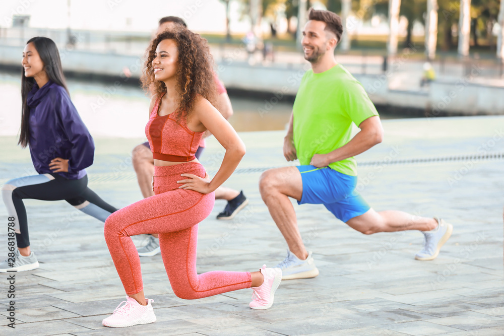 Group of young sporty people training together outdoors