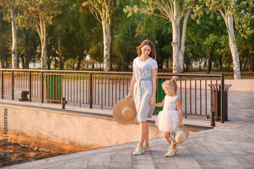 Happy mother and her little daughter near river