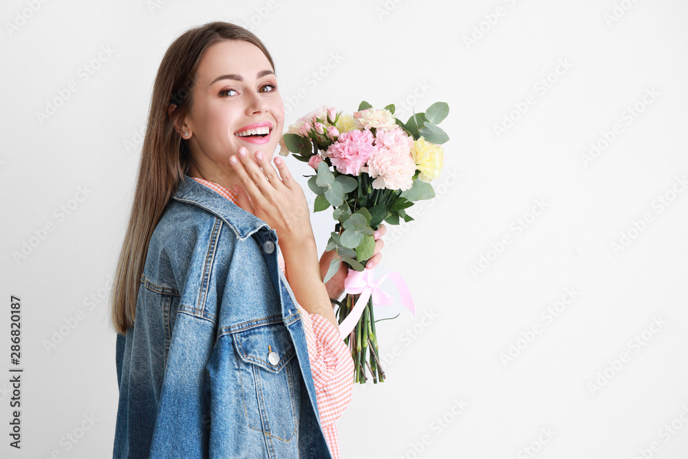 美丽的年轻女子，浅色背景上有一束康乃馨花